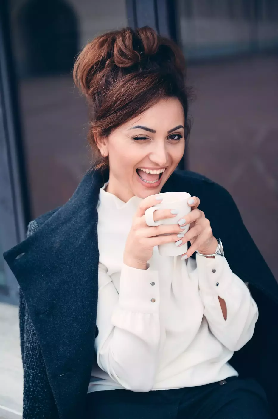 Donna elegante seduta alla terrazza di un bar che beve una bevanda calda